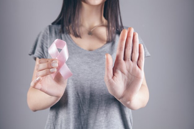 Ein Mädchen hält ein Band mit einem Krebszeichen in der Hand und zeigt mit der anderen Hand ein Stoppschild