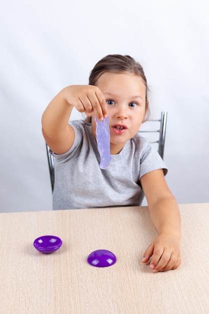 Ein Mädchen hält einen lila Schleim, der auf den Tisch fällt, Anti-Stress-Spiele.