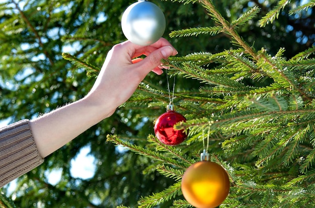 Ein Mädchen hängt Weihnachtskugeln an den Weihnachtsbaum. Hintergrund des neuen Jahres.