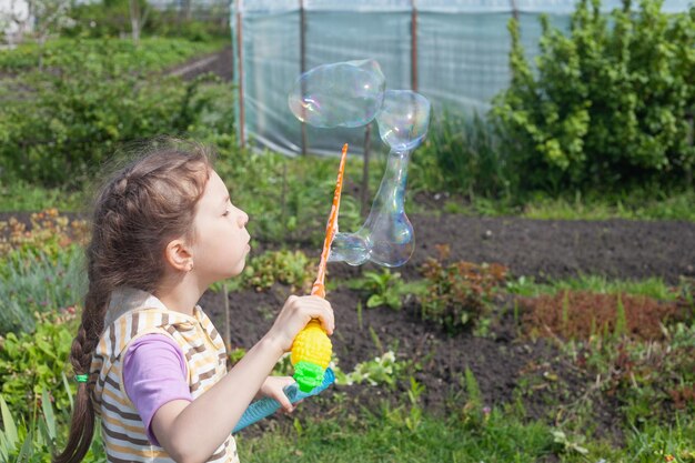 Ein Mädchen im Garten bläst große Seifenblasen auf