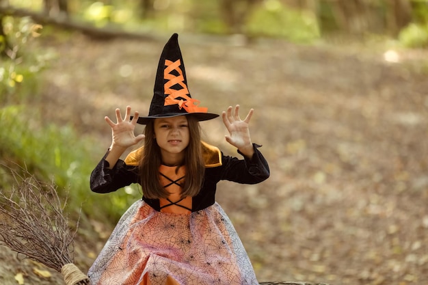 Ein Mädchen im Hexenkostüm im Herbstpark an Halloween Süßes oder Saures Unterhaltungskonzept für Kinder