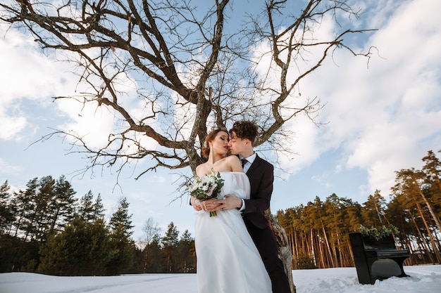 Ein Mädchen im Hochzeitskleid und ein junger Mann stehen neben dem Klavier. Winterfotografie