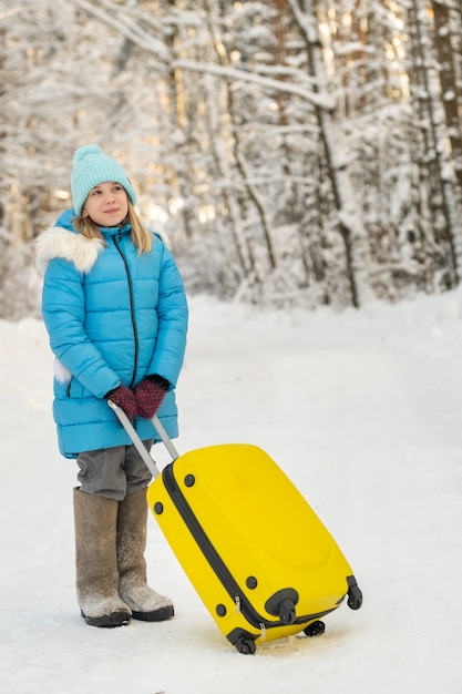 Ein Mädchen im Winter in Filzstiefeln geht mit einem Koffer an einem frostigen Schneetag