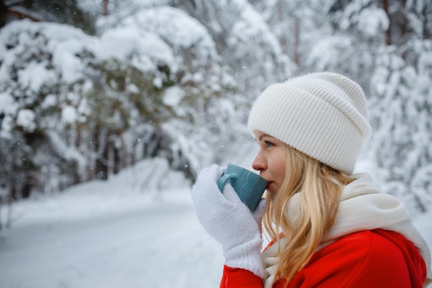 Ein Mädchen im Winterwald, eine Blondine in roten Kleidern, ein lustiger Spaziergang in der Natur