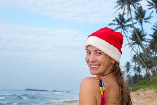 Ein Mädchen in Badeanzug und Weihnachtsmütze auf dem Meer