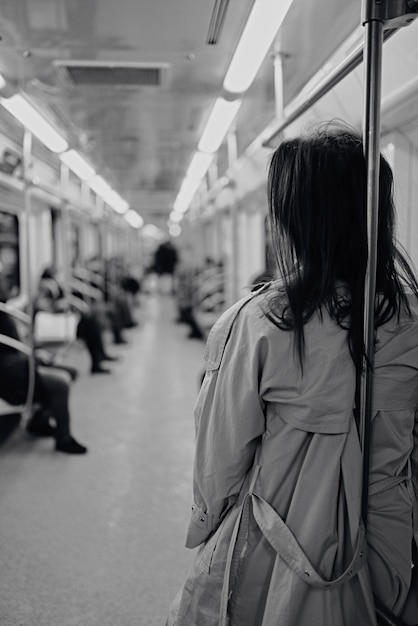 Foto ein mädchen in einem beigen trenchcoat fährt in einem u-bahn-wagen.bw