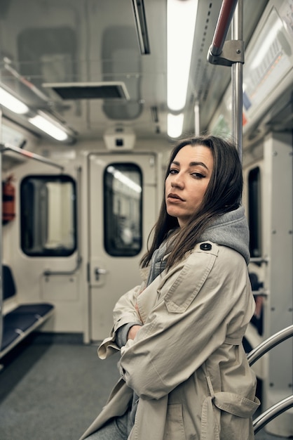 Ein Mädchen in einem beigen Trenchcoat fährt in einem U-Bahn-Wagen.