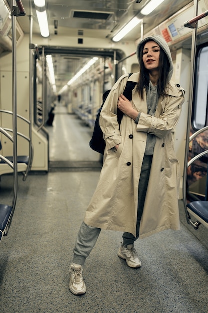 Ein Mädchen in einem beigen Trenchcoat fährt in einem U-Bahn-Wagen.