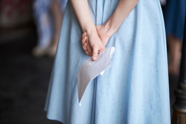 Ein Mädchen in einem blauen Kleid hält während einer Prüfung ein Blatt Papier hinter ihrem Rücken