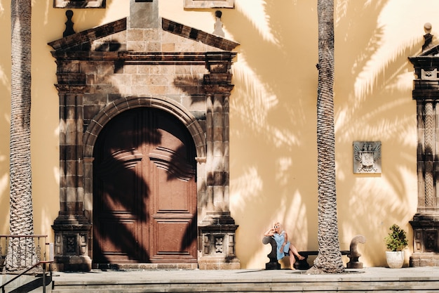 Foto ein mädchen in einem blauen kleid sitzt an einem sonnigen tag auf einer bank in der altstadt von garachico auf der insel teneriffa