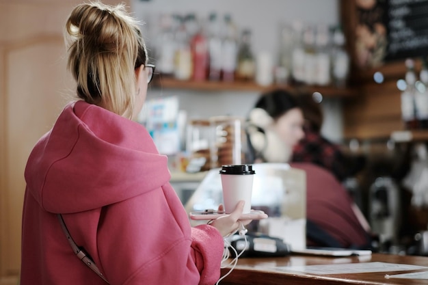Ein Mädchen in einem Café steht neben der Theke und bestellt Kaffee.