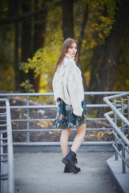 Ein Mädchen in einem grauen Strickpullover vor dem Hintergrund eines Herbstparks