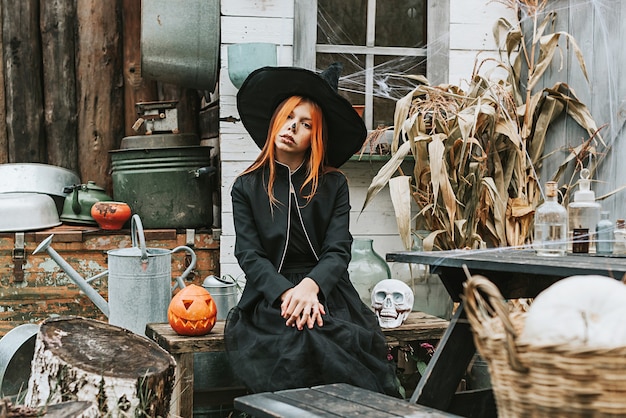 Ein Mädchen in einem Hexenkostüm amüsiert sich auf einer Halloween-Party auf der dekorierten Veranda