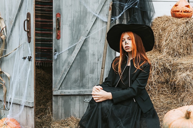 Ein Mädchen in einem Hexenkostüm amüsiert sich auf einer Halloween-Party auf der dekorierten Veranda