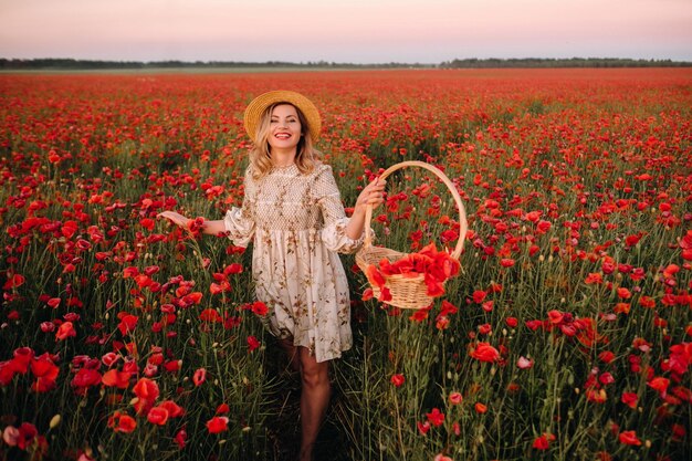 Ein Mädchen in einem Kleid mit Hut und mit einem Korb in einem Feld mit Mohnblumen