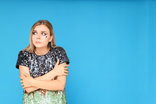 Ein Mädchen in einem Kleid mit Pailletten, sehr verängstigt auf blauem Hintergrund