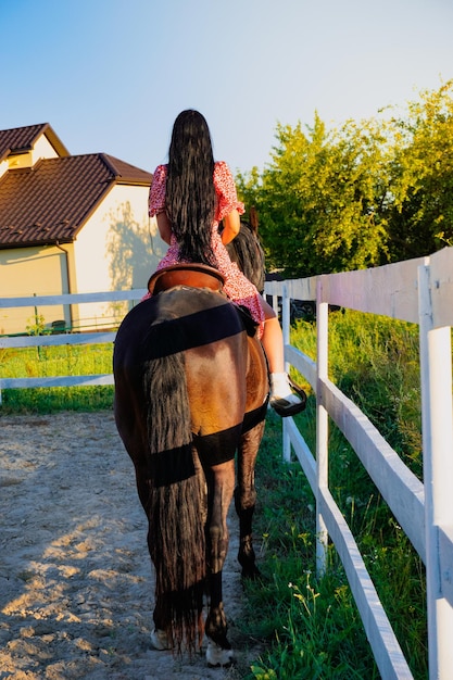 Ein Mädchen in einem Kleid reitet auf einem Pferd.