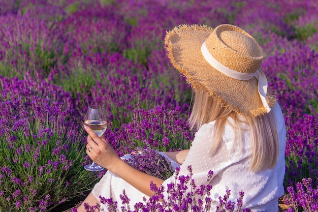 Ein Mädchen in einem Lavendelfeld gießt Wein in ein Glas Entspannung