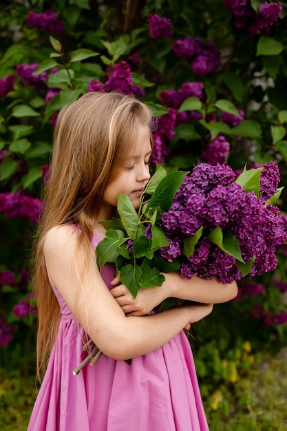 Ein Mädchen in einem lila Kleid hält einen Strauß lila Blumen.