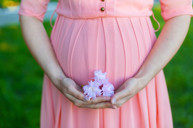 Ein Mädchen in einem rosa Kleid hält eine Sakura-Blume in ihren Händen