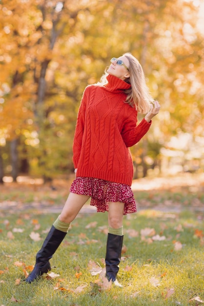 Ein Mädchen in einem roten Pullover geht im Herbst im Park spazieren, das Konzept der Herbstsaison