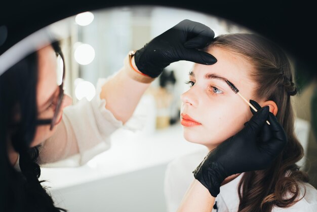 Foto ein mädchen in einem schönheitssalon lässt sich bei einer augenbrauenlaminierung mit weißer paste beschmieren