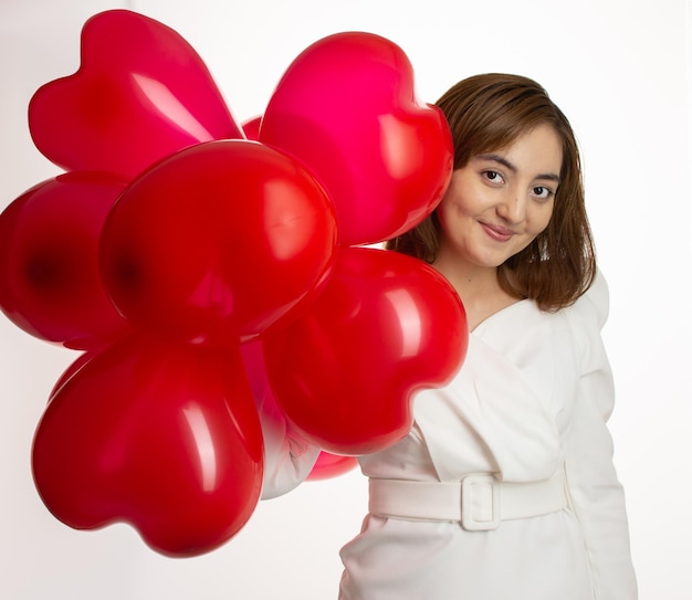 Ein Mädchen in einem weißen Hintergrund hält einen herzförmigen Ballon in der Hand