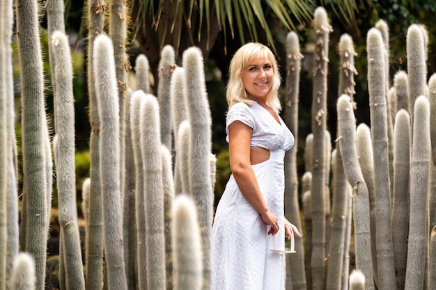 Ein Mädchen in einem weißen Kleid auf dem Hintergrund der riesigen Kakteen auf der Insel Teneriffa.