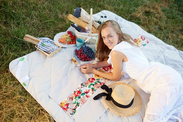 Ein Mädchen in einem weißen Kleid liegt im Sommer auf einer weißen Decke im Gras