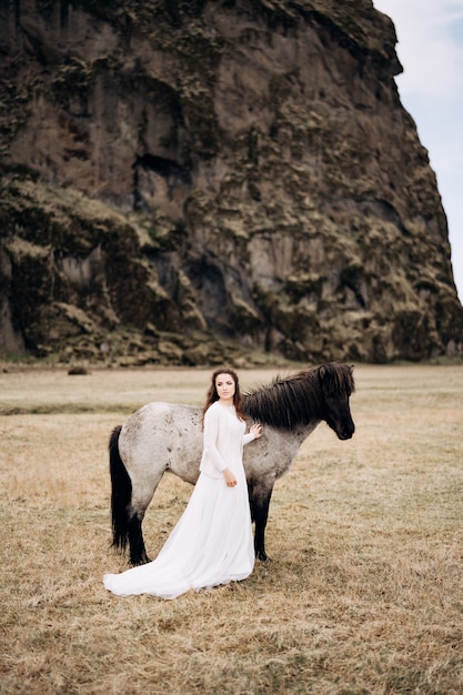 Ein Mädchen in einem weißen Kleid neben einem weißen Pferd