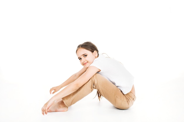 Foto ein mädchen in einem weißen t-shirt, hosen mit langen haaren auf weißem hintergrund, studio, teenager