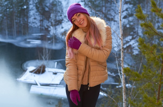 Ein Mädchen in einem Winterwald in der Nähe eines Sees mit blauem Eis und rocks.russischer Winter.