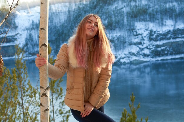 Ein Mädchen in einem Winterwald in der Nähe eines Sees mit blauem Eis und rocks.russischer Winter.
