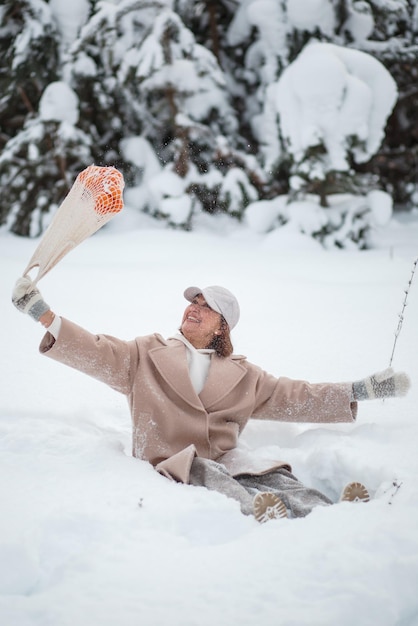 Ein Mädchen in einem Winterwald mit einer Tüte Mandarinen, die im Schnee liegen