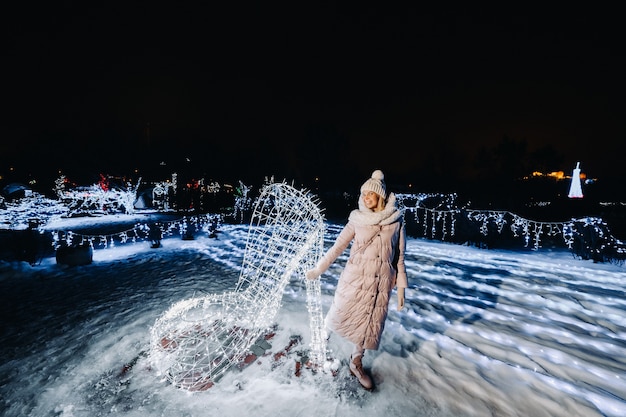 Ein Mädchen in einer grauen Jacke im Winter mit brennenden Abendlichtern auf der Weihnachtsstraße