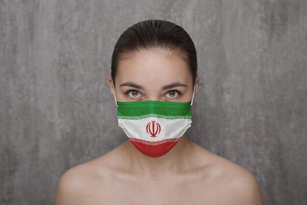 Ein Mädchen in einer Maske im Gesicht mit der Flagge des Iran