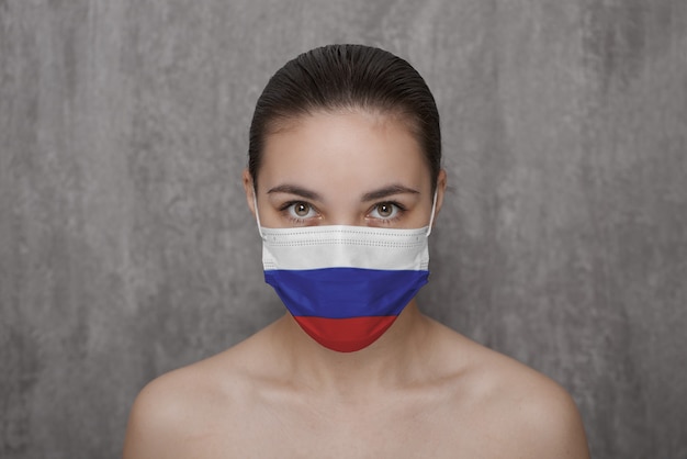 Ein Mädchen in einer Maske im Gesicht mit einer russischen Flagge