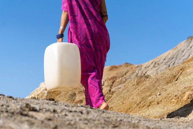 Ein Mädchen in ethnischer Kleidung geht mit einem Plastikkanister Wasser holen