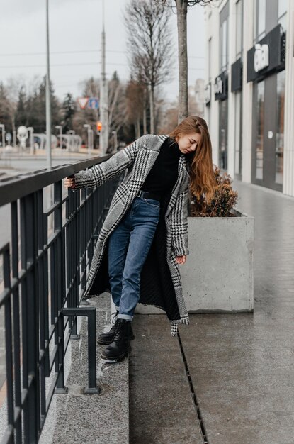 ein mädchen in grauem mantel und jeans hält sich am handlauf fest