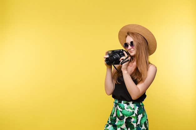 Ein Mädchen in Hut und Sonnenbrille mit Kamera.