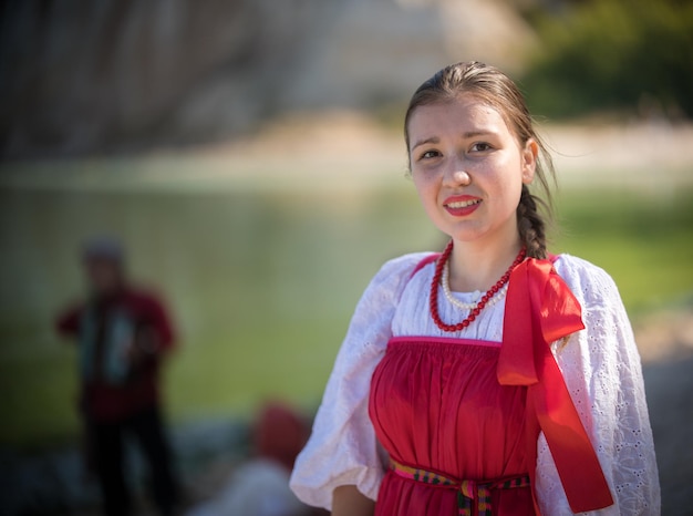 Foto ein mädchen in roter russischer tracht steht auf dem hintergrund einer erstaunlichen landschaft, nahaufnahme