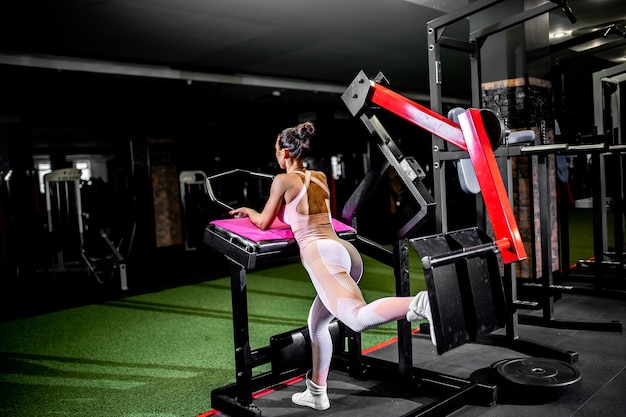 Ein Mädchen in Sportbekleidung in einem professionellen Fitnessstudio trainiert mit Fitnessgeräten.