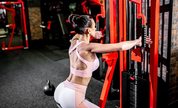 Ein Mädchen in Sportbekleidung in einem professionellen Fitnessstudio trainiert mit Fitnessgeräten