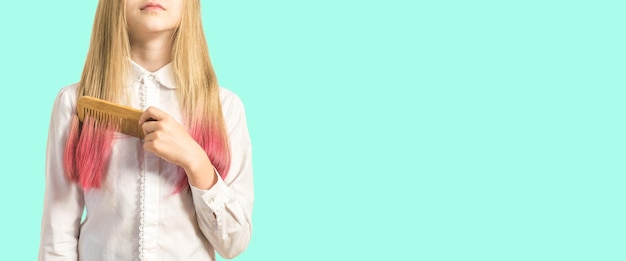 Ein Mädchen kämmt ihr gefärbtes Haar auf hellem Hintergrund