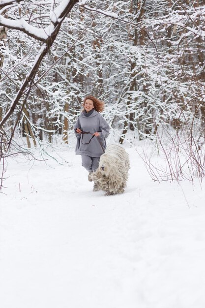 Ein Mädchen läuft mit einem Hund durch den Wald