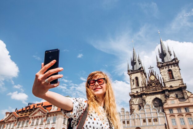 Ein Mädchen macht ein Selfie vor dem Hintergrund der Tyn-Kirche. Foto am Telefon in Prag. Schöne junge Dame, die in Prag reist. Glückliche Touristin machen ein Selfie.