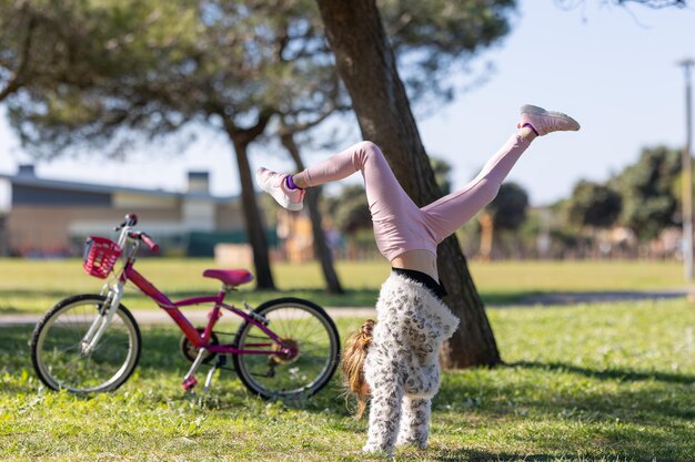 Foto ein mädchen macht einen handstand im gras neben einem fahrrad