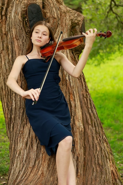 Ein Mädchen mit asiatischem Aussehen spielt Geige in der Natur. Foto in hoher Qualität