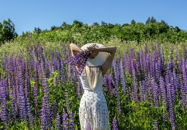 Ein Mädchen mit blonden Haaren in einem Feld von Lupinen