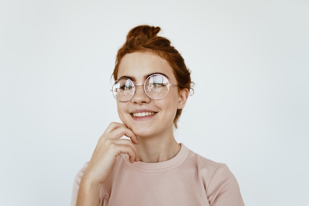 Ein Mädchen mit Brille zur Verbesserung des Sehvermögens lächelt wunderschön und zeigt schöne Zähne. grauer Hintergrund